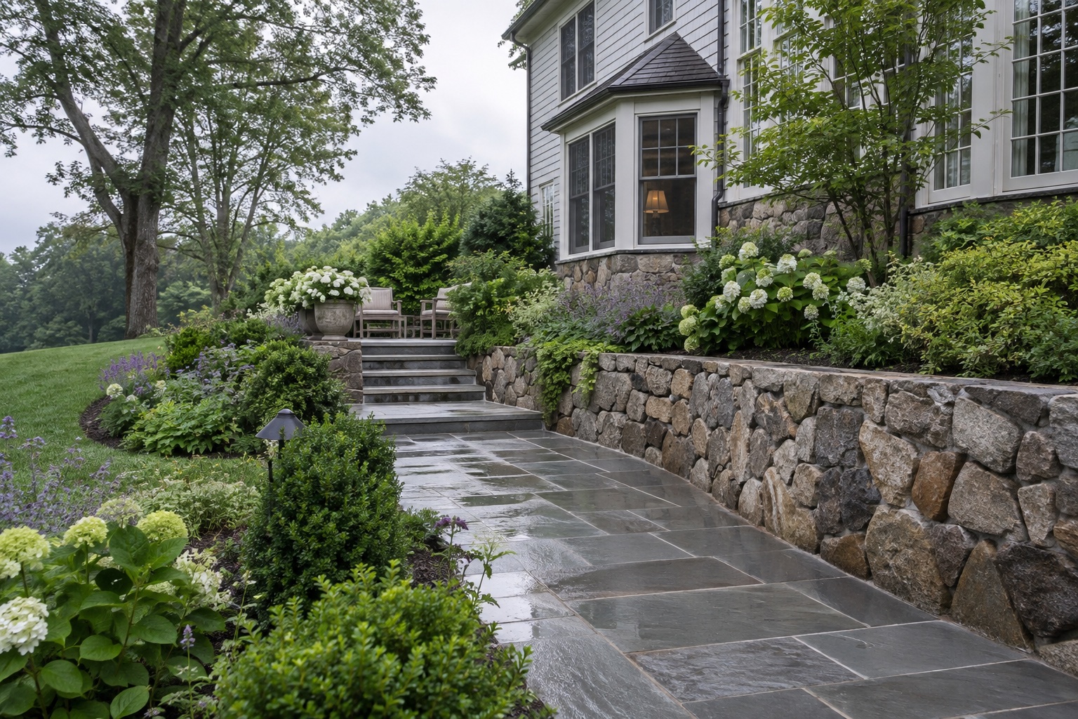 Bluestone walkway and fieldstone retaining wall surrounded by established plantings